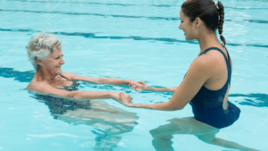 Ergothérapie aquatique. Femme âgée s'entraînant avec une maître nageuse dans la piscine.
