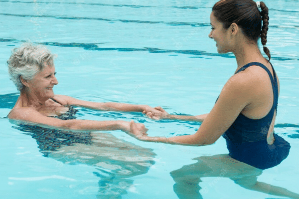 Ergothérapie aquatique. Femme âgée s'entraînant avec une maître nageuse dans la piscine.
